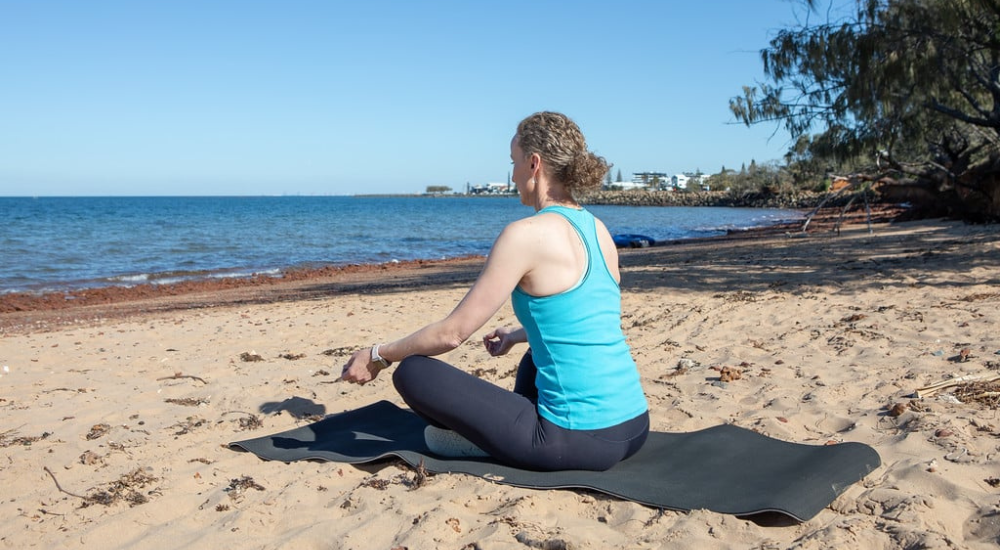 Photo of woman meditating by the beach